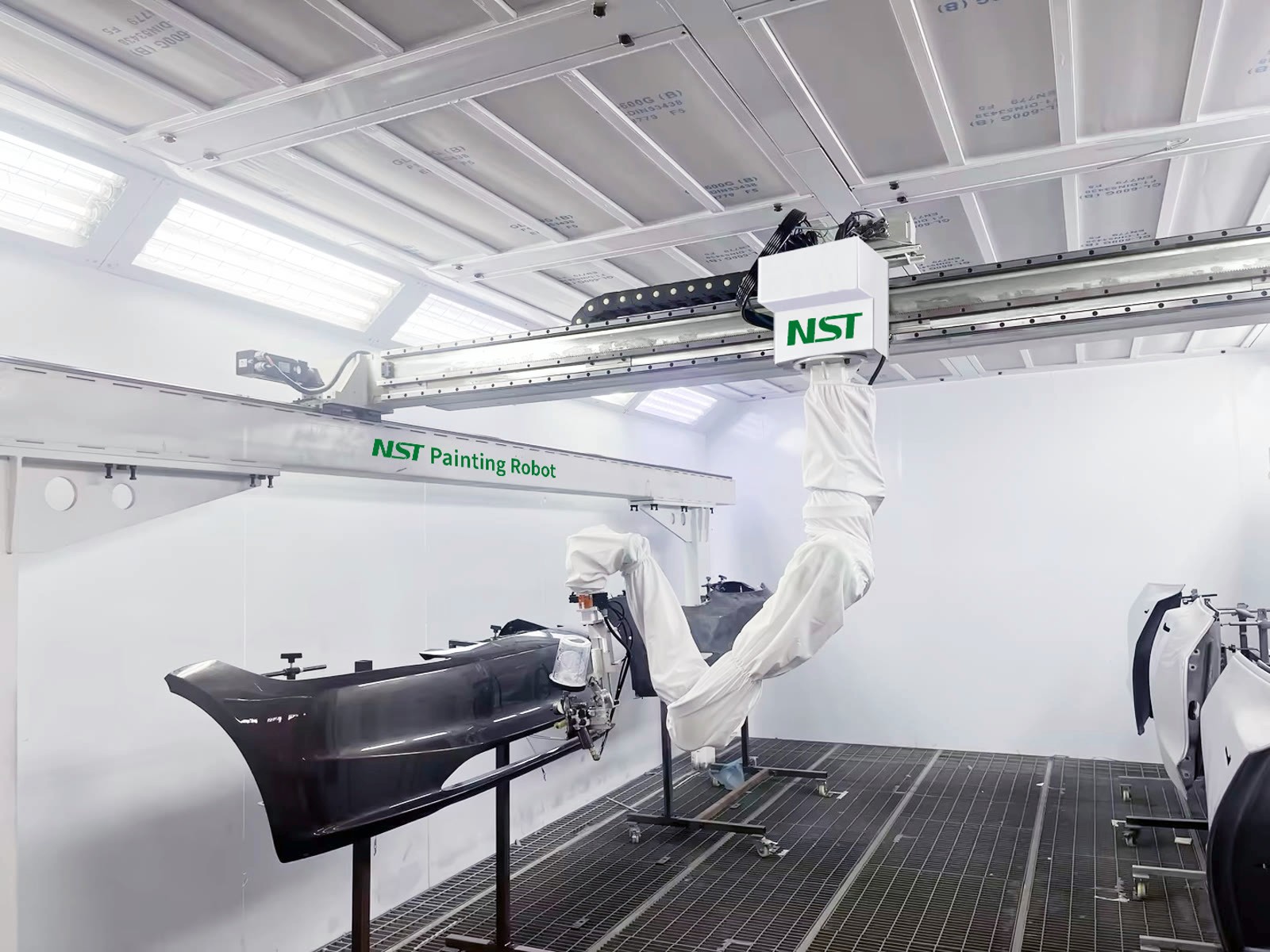 The NST robot spraying a black bumper while door panels wait on stands in the same booth cycle