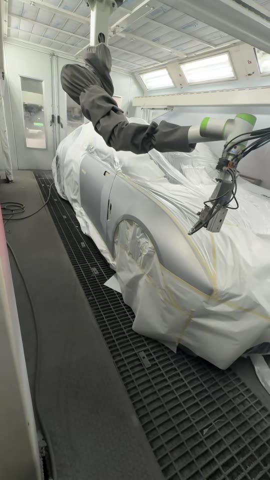Close-up of the NST robot arm spraying in the booth